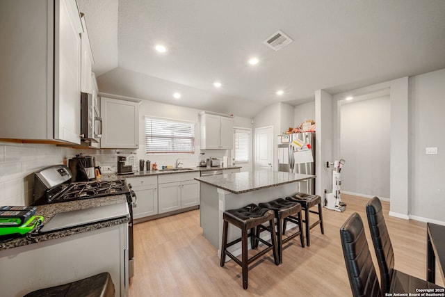 31646 Untrodden Way, Bulverde, TX 78163 - kitchen with stainless steel appliances, light wood finished floors, tasteful backsplash, a breakfast bar, and a center island