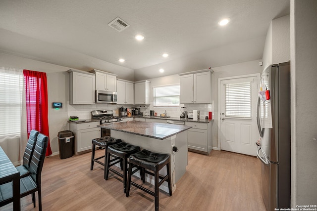 31646 Untrodden Way, Bulverde, TX 78163 - kitchen featuring appliances with stainless steel finishes, light wood-style flooring, a breakfast bar, tasteful backsplash, and recessed lighting