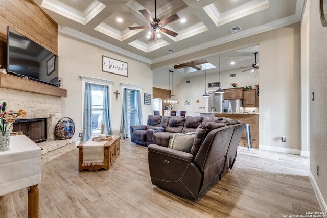 688 Double Gate Rd, Castroville, TX 78009 - living area with a ceiling fan, a high ceiling, a stone fireplace, crown molding, and light wood-type flooring