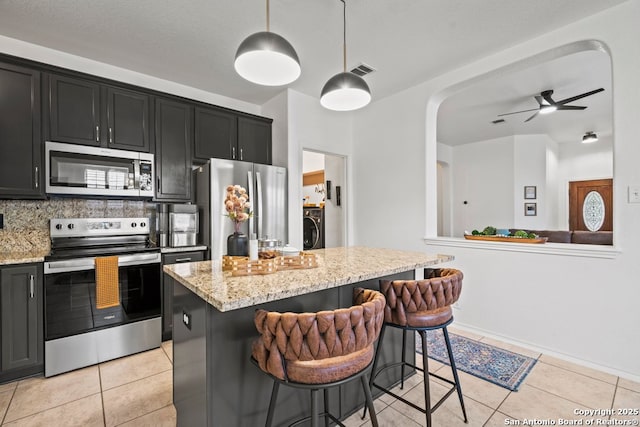 788 San Luis, New Braunfels, TX 78132 - kitchen with stainless steel appliances, washer / clothes dryer, dark cabinets, and light stone counters