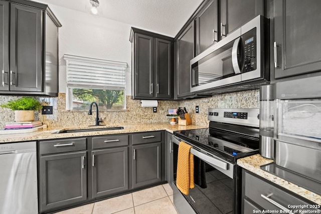 788 San Luis, New Braunfels, TX 78132 - kitchen with stainless steel appliances, a sink, light tile patterned flooring, tasteful backsplash, and light stone counters