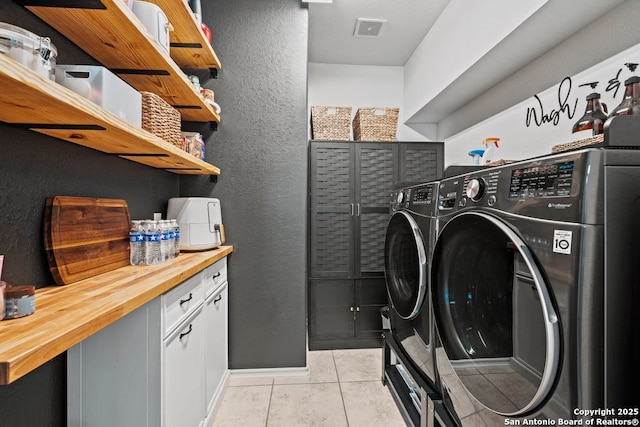 788 San Luis, New Braunfels, TX 78132 - laundry area with washing machine and dryer, light tile patterned flooring, baseboards, a textured wall, and cabinet space