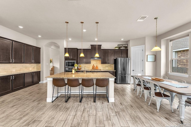 11926 Tower Crk, San Antonio, TX 78253 - kitchen featuring stainless steel appliances, arched walkways, dark brown cabinets, light wood-type flooring, and recessed lighting