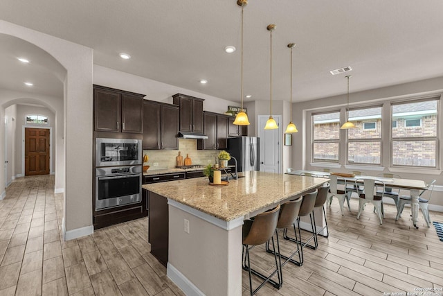 11926 Tower Crk, San Antonio, TX 78253 - kitchen with appliances with stainless steel finishes, wood finish floors, under cabinet range hood, dark brown cabinetry, and recessed lighting