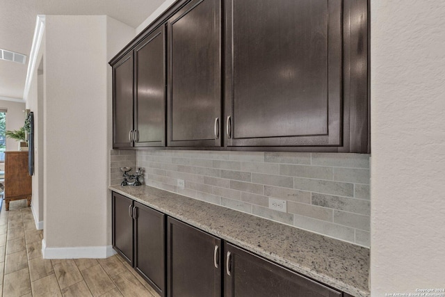 11926 Tower Crk, San Antonio, TX 78253 - kitchen with decorative backsplash, light stone counters, dark brown cabinetry, and baseboards