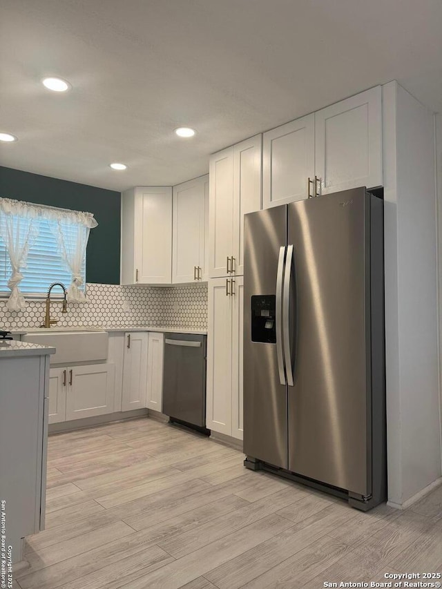 430 Indigo, San Antonio, TX 78216 - kitchen featuring appliances with stainless steel finishes, a sink, light wood-type flooring, white cabinets, and recessed lighting