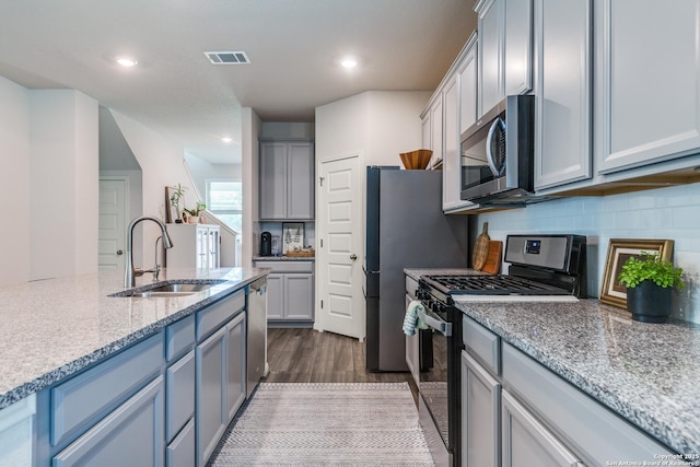12918 Lilly Pass, San Antonio, TX 78254 - kitchen featuring stainless steel appliances, a sink, dark wood finished floors, backsplash, and light stone counters