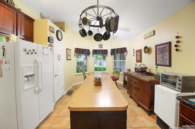 9519 Braun Shr, San Antonio, TX 78250 - kitchen featuring white refrigerator with ice dispenser, a center island, light tile patterned flooring, and light countertops