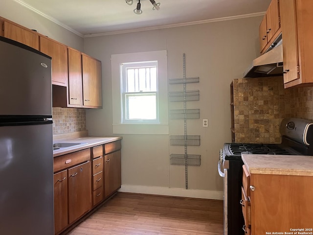 1024 W Mistletoe, San Antonio, TX 78201 - kitchen featuring freestanding refrigerator, gas range oven, under cabinet range hood, light wood-style flooring, and decorative backsplash