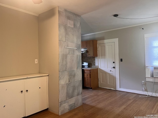 1024 W Mistletoe, San Antonio, TX 78201 - kitchen with under cabinet range hood, wood finished floors, ornamental molding, light countertops, and brown cabinetry