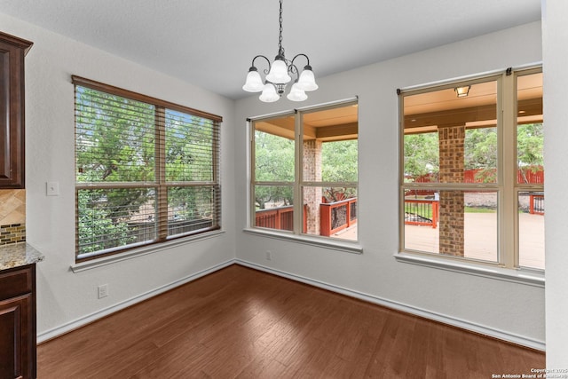 26011 Red Heron, San Antonio, TX 78261 - unfurnished dining area with healthy amount of natural light, dark wood-style floors, a chandelier, and baseboards