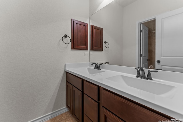 26011 Red Heron, San Antonio, TX 78261 - bathroom with double vanity, a textured wall, and baseboards