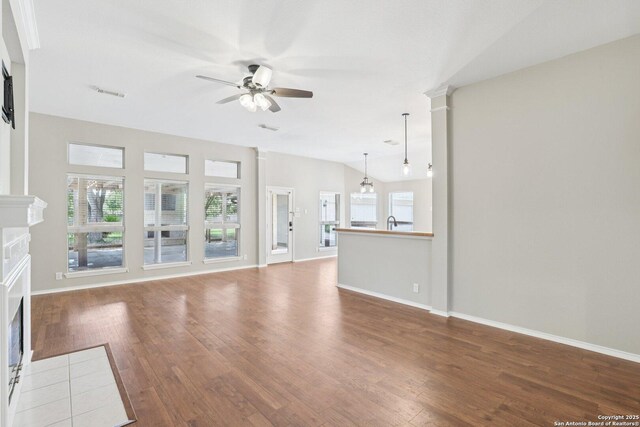 251 Las Brisas, Seguin, TX 78155 - unfurnished living room featuring a tiled fireplace, a ceiling fan, wood finished floors, and baseboards