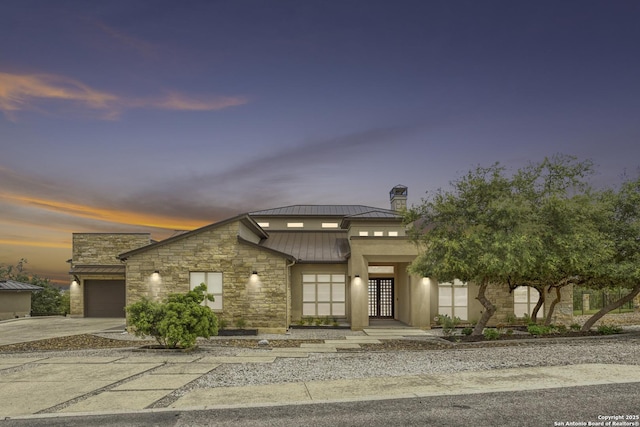 8602 Terra Mont Way, San Antonio, TX 78255 - view of front of house featuring a standing seam roof, stone siding, driveway, an attached garage, and a chimney