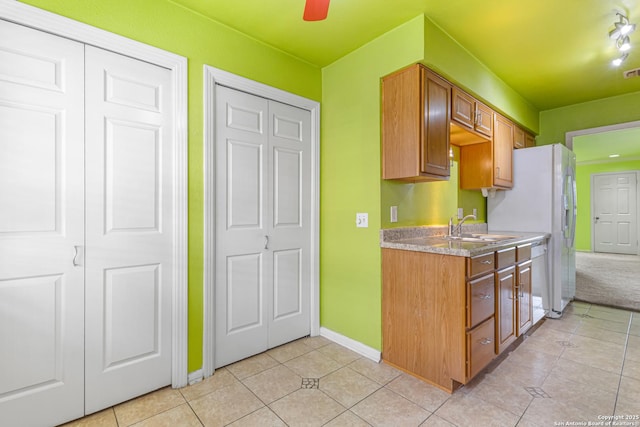 165 W Rampart Unit 204, San Antonio, TX 78216 - kitchen with light tile patterned floors, a sink, baseboards, brown cabinetry, and white fridge with ice dispenser