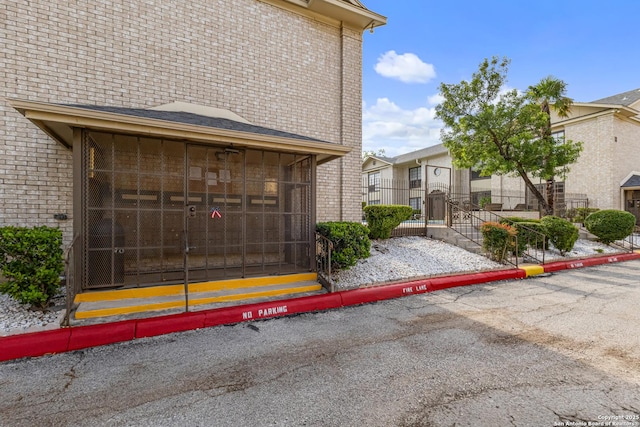 165 W Rampart Unit 204, San Antonio, TX 78216 - view of home's exterior with brick siding, uncovered parking, a residential view, and a sunroom