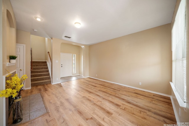 9026 Foxgrove Way, San Antonio, TX 78251 - unfurnished living room featuring arched walkways, light wood finished floors, baseboards, and stairs
