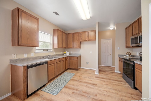 9026 Foxgrove Way, San Antonio, TX 78251 - kitchen with stainless steel appliances, a sink, light wood-style flooring, baseboards, and brown cabinets