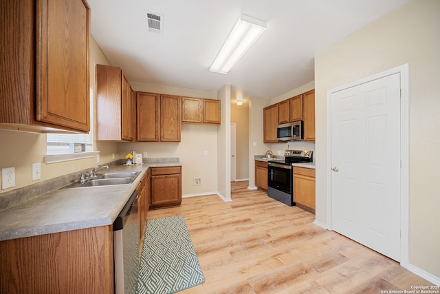 9026 Foxgrove Way, San Antonio, TX 78251 - kitchen featuring appliances with stainless steel finishes, a sink, brown cabinetry, light wood finished floors, and baseboards