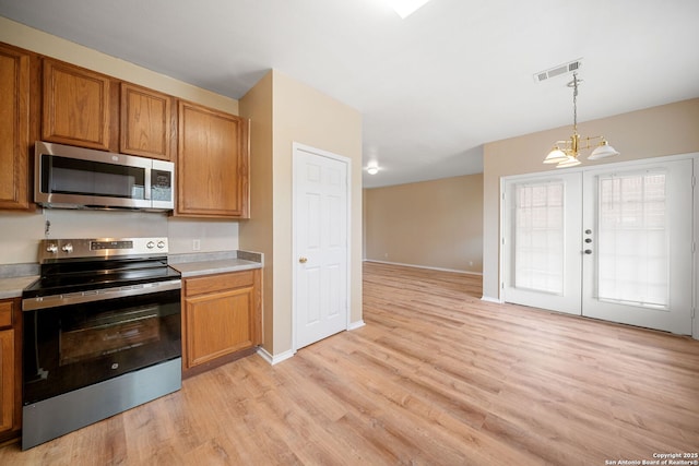 9026 Foxgrove Way, San Antonio, TX 78251 - kitchen featuring stainless steel appliances, light wood-type flooring, a chandelier, and brown cabinetry