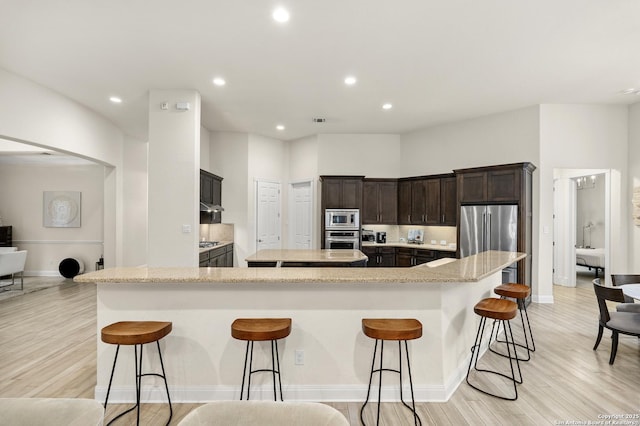 24706 Moorland, San Antonio, TX 78257 - kitchen featuring stainless steel appliances, a spacious island, light wood-style flooring, a breakfast bar, and recessed lighting