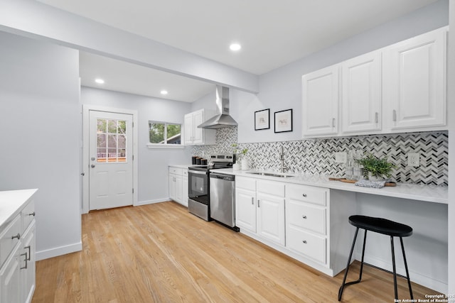 131 New Hvn, San Antonio, TX 78209 - kitchen featuring wall chimney range hood, stainless steel appliances, a sink, tasteful backsplash, and light wood-style floors