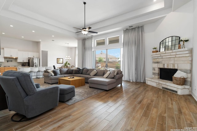 1512 Aubrey Pt, San Antonio, TX 78260 - living area with light wood-type flooring, a tray ceiling, ceiling fan, a fireplace, and recessed lighting