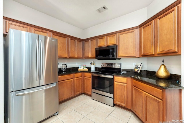 9106 Thomas York, San Antonio, TX 78251 - kitchen featuring stainless steel appliances, brown cabinets, light tile patterned floors, and dark stone counters