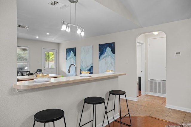1035 Magnolia Hl, San Antonio, TX 78251 - kitchen with a breakfast bar, arched walkways, baseboards, decorative light fixtures, and light countertops