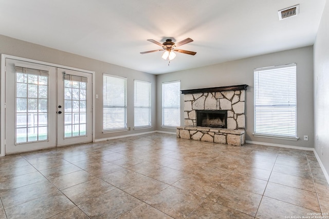 18039 Shady Knl, San Antonio, TX 78258 - unfurnished living room featuring french doors, ceiling fan, tile patterned flooring, a stone fireplace, and baseboards