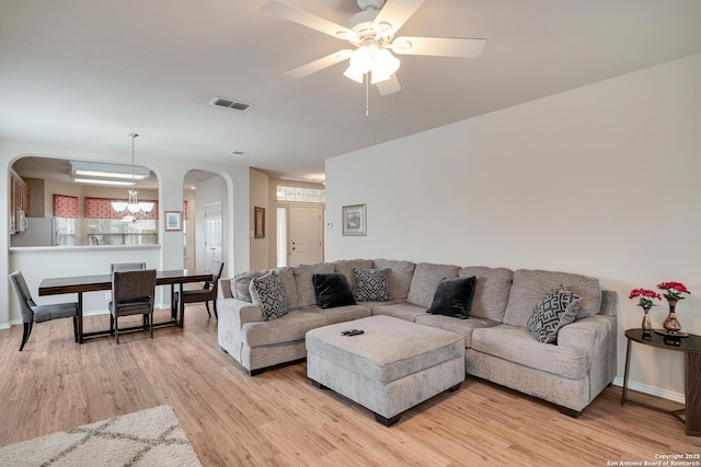 125 Wright Cv, Cibolo, TX 78108 - living room with arched walkways, light wood-type flooring, a ceiling fan, a chandelier, and baseboards