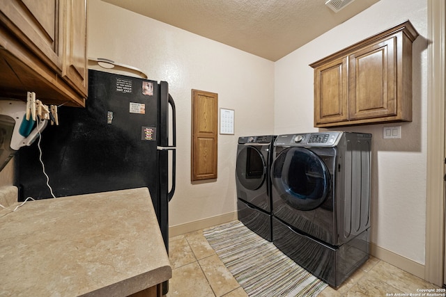 438 County Road 367, Hondo, TX 78861 - washroom with washing machine and clothes dryer, baseboards, cabinet space, a textured ceiling, and light tile patterned floors