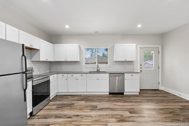 129 Odell, San Antonio, TX 78212 - kitchen featuring appliances with stainless steel finishes, a sink, dark countertops, white cabinetry, and decorative backsplash