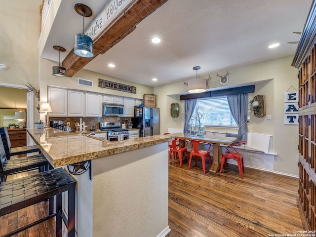 1614 Sunnybrook, New Braunfels, TX 78130 - kitchen with appliances with stainless steel finishes, a peninsula, white cabinetry, wood finished floors, and backsplash