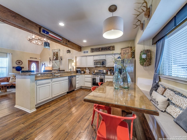 1614 Sunnybrook, New Braunfels, TX 78130 - kitchen featuring appliances with stainless steel finishes, a peninsula, white cabinetry, dark wood-style floors, and a chandelier