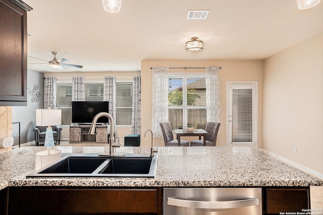 2196 New Castle, New Braunfels, TX 78130 - kitchen featuring stainless steel dishwasher, a sink, dark brown cabinets, open floor plan, and light stone countertops
