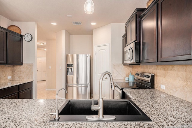 2196 New Castle, New Braunfels, TX 78130 - kitchen with appliances with stainless steel finishes, a sink, dark brown cabinetry, light stone countertops, and backsplash