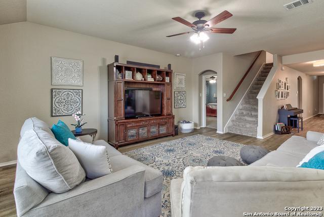 331 Primrose, New Braunfels, TX 78132 - living room with arched walkways, a ceiling fan, stairs, baseboards, and wood finished floors