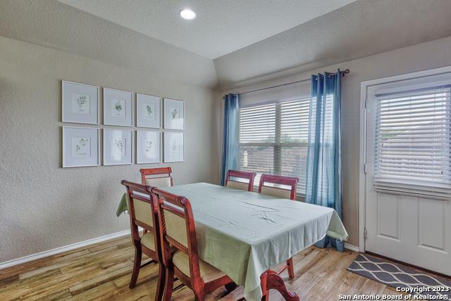 331 Primrose, New Braunfels, TX 78132 - dining space with baseboards, light wood-type flooring, vaulted ceiling, and a textured wall