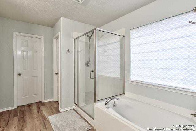 331 Primrose, New Braunfels, TX 78132 - full bathroom featuring a shower stall, a garden tub, wood finished floors, and a textured ceiling