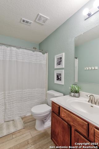 331 Primrose, New Braunfels, TX 78132 - full bath featuring vanity, toilet, wood finished floors, a textured ceiling, and a shower with curtain