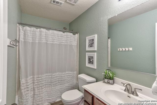 331 Primrose, New Braunfels, TX 78132 - bathroom featuring vanity, toilet, a textured wall, and a textured ceiling