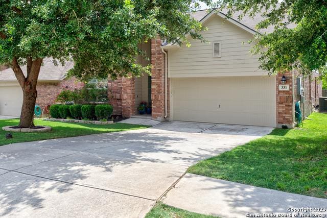 331 Primrose, New Braunfels, TX 78132 - view of front of property with concrete driveway, brick siding, a garage, a front lawn, and central AC