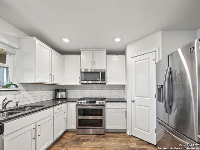 22146 Pivot Pt, San Antonio, TX 78261 - kitchen with stainless steel appliances, a sink, white cabinets, dark stone countertops, and recessed lighting