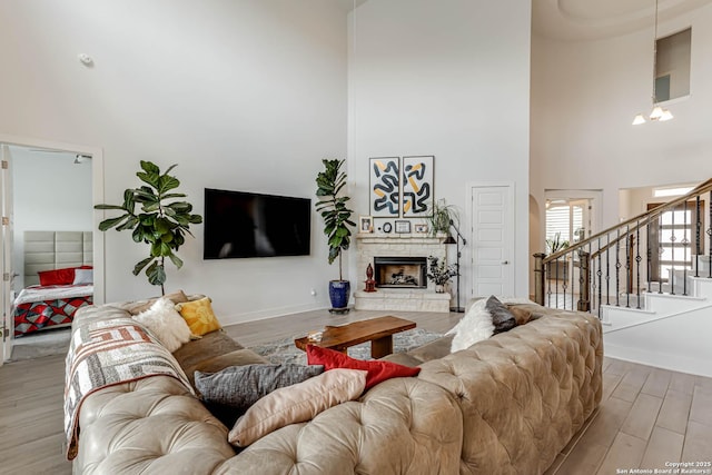 17703 San Felipe Bay, San Antonio, TX 78255 - living area featuring a towering ceiling, wood finished floors, stairway, a stone fireplace, and baseboards
