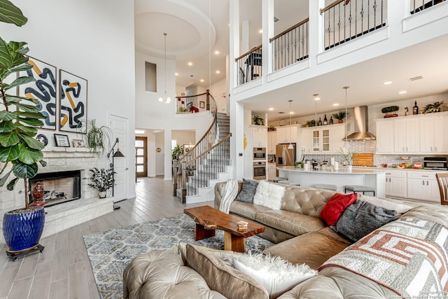 17703 San Felipe Bay, San Antonio, TX 78255 - living room with a towering ceiling, stairway, light wood-style floors, and a fireplace
