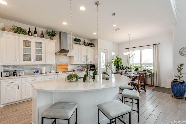 17703 San Felipe Bay, San Antonio, TX 78255 - kitchen featuring wall chimney range hood, a breakfast bar area, tasteful backsplash, recessed lighting, and white cabinets