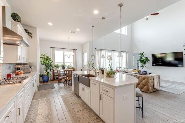 17703 San Felipe Bay, San Antonio, TX 78255 - kitchen featuring appliances with stainless steel finishes, a sink, wall chimney exhaust hood, light wood finished floors, and recessed lighting