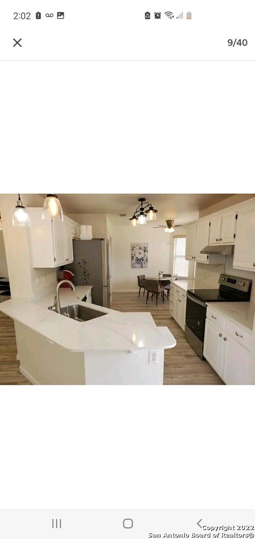 11427 Baltic Dr, San Antonio, TX 78213 - kitchen featuring stainless steel appliances, a sink, under cabinet range hood, white cabinetry, and a peninsula