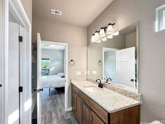 1229 Marlys, Canyon Lake, TX 78133 - ensuite bathroom featuring a textured wall, vanity, wood finished floors, and baseboards